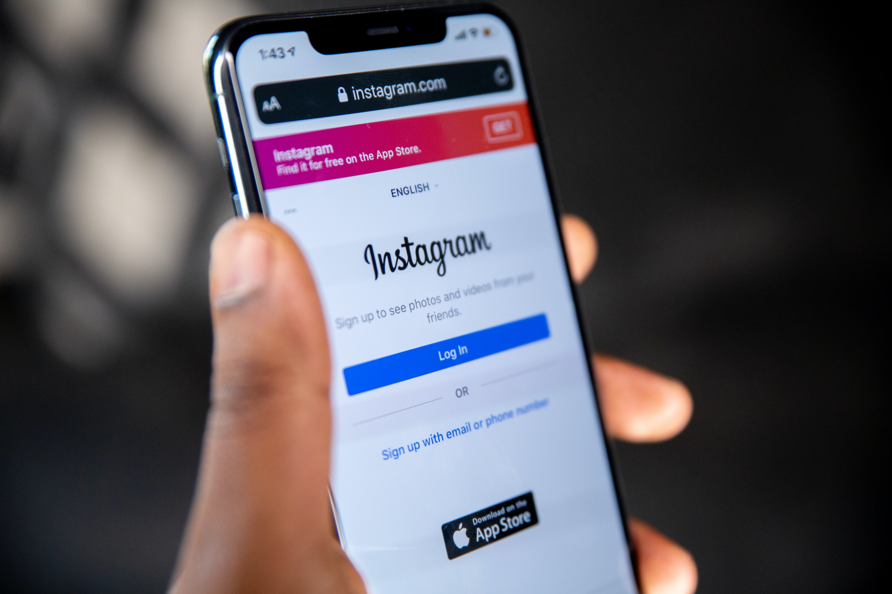 Handy in der Hand. Das Handy zeigt die Startseite von Instagram.